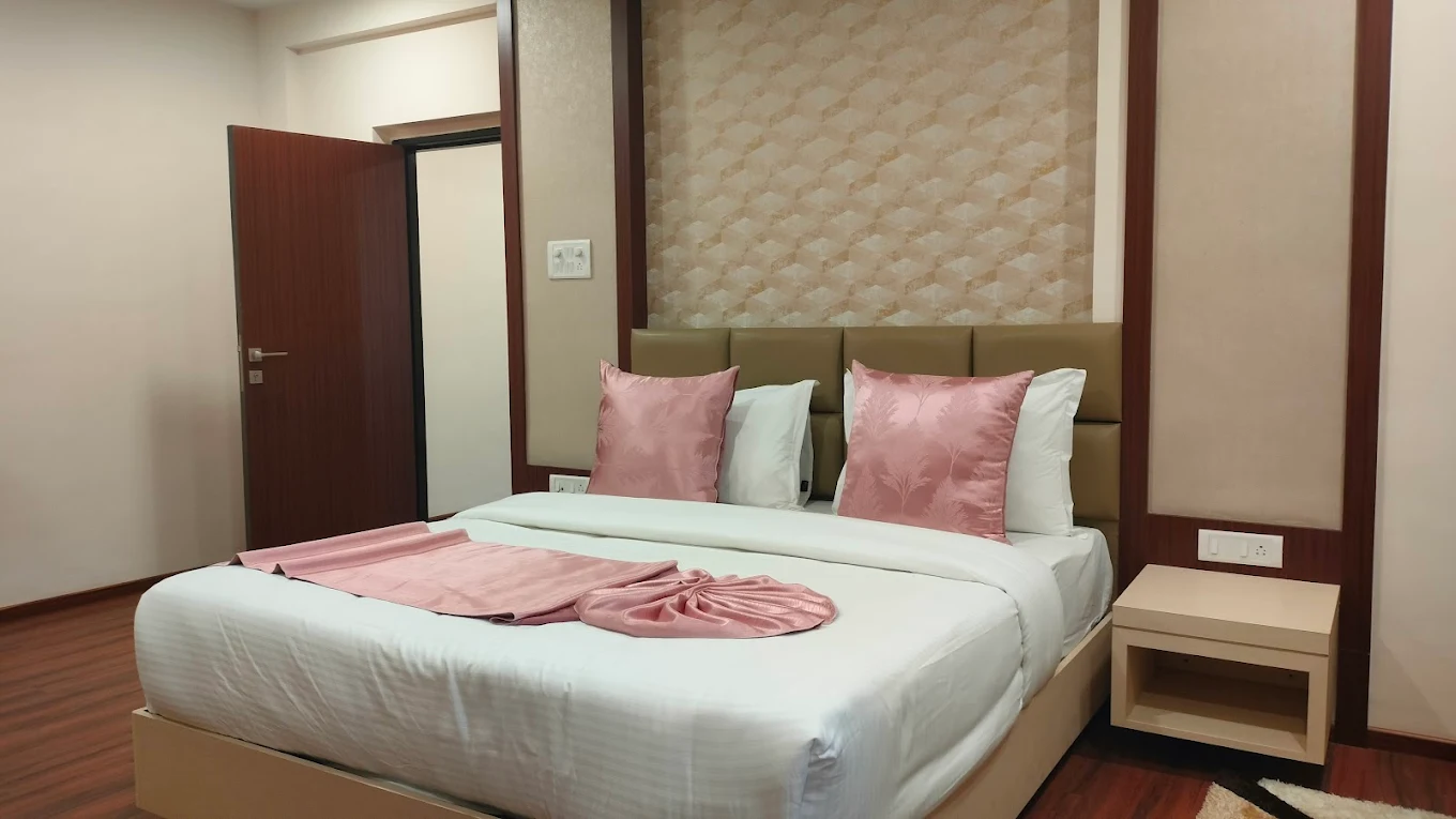 A cozy and well-furnished standard room with a queen-sized bed, a work desk, and a comfortable armchair, designed for a relaxing stay at Hotel Swamiraj.
