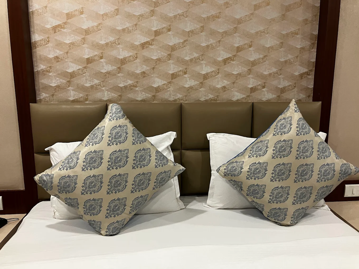 An elegant family room featuring two double beds, a seating area, and colorful decor, designed to accommodate families comfortably at Hotel Swamiraj.